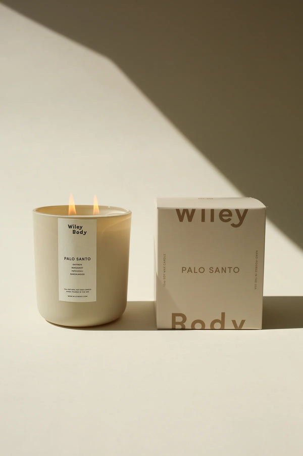 Płonąca świeca sojowa Wiley Body Palo Santo w beżowym słoiku i pudełko.