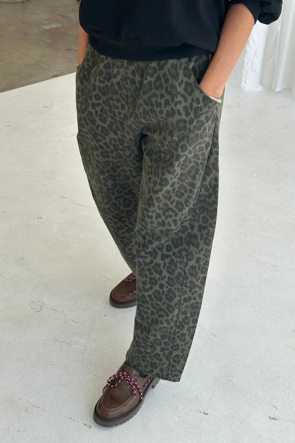 Sylwetka w spodniach Le Bon Shoppe Arc Pants Fern Leopard z dłońmi w kieszeniach.