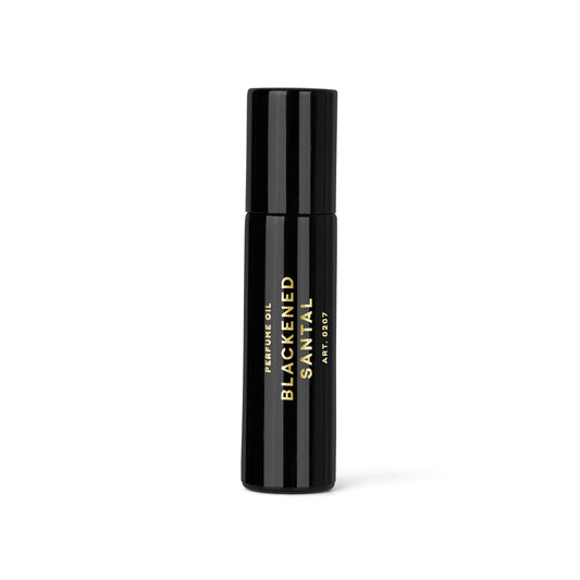 Czarna szklana butelka perfum w olejku Blackened Santal marki RAAW Alchemy ustawiona na jasnym tle.